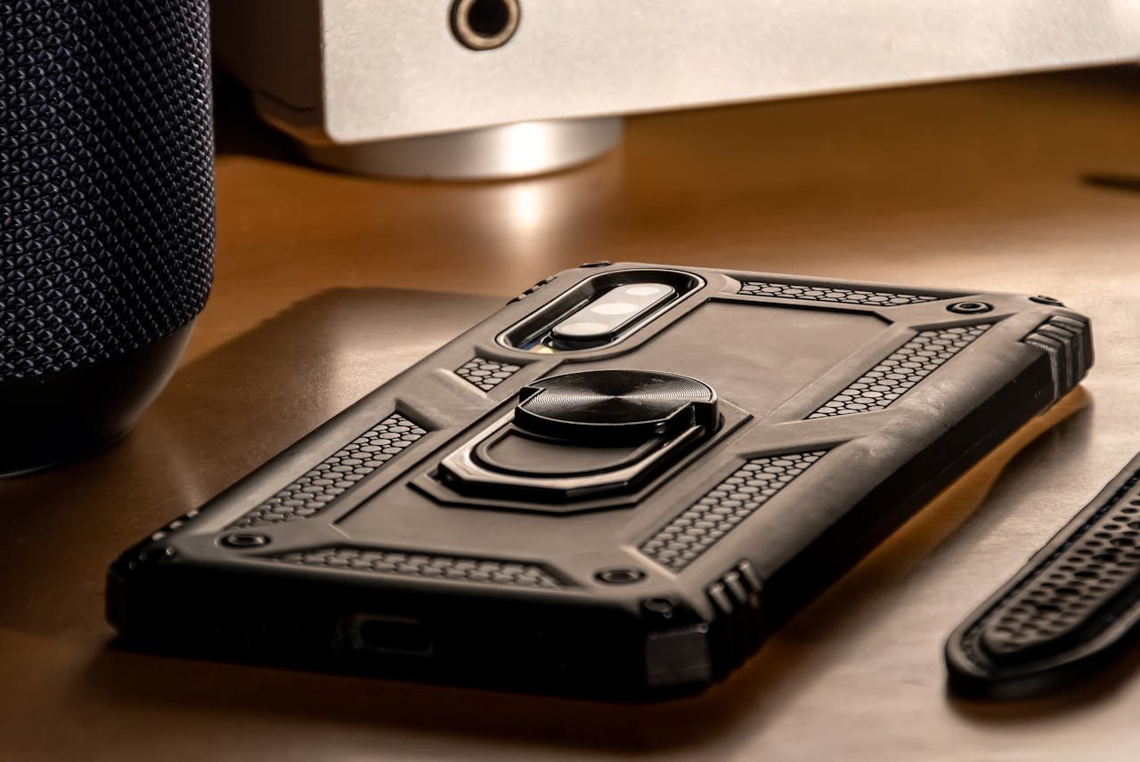 A detailed close-up view of a smartphone with a rugged case lying on a desk, showcasing modern technology.